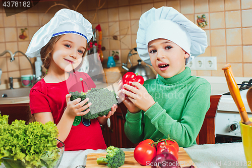 Image of happy family funny kids are preparing the a fresh vegetable salad in the kitchen