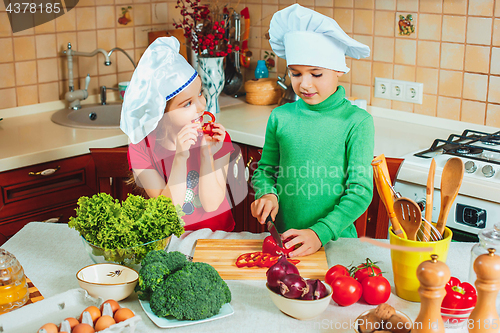 Image of happy family funny kids are preparing the a fresh vegetable salad in the kitchen