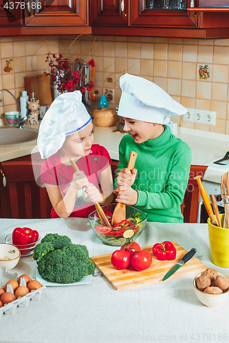 Image of happy family funny kids are preparing the a fresh vegetable salad in the kitchen
