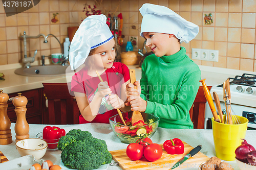 Image of happy family funny kids are preparing the a fresh vegetable salad in the kitchen