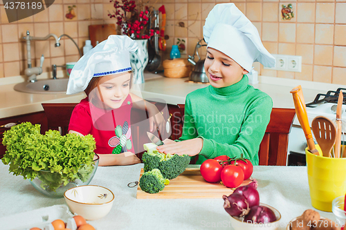 Image of happy family funny kids are preparing the a fresh vegetable salad in the kitchen