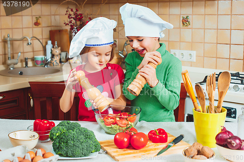 Image of happy family funny kids are preparing the a fresh vegetable salad in the kitchen