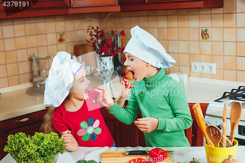 Image of happy family funny kids are preparing the a fresh vegetable salad in the kitchen