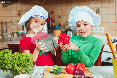 Image of happy family funny kids are preparing the a fresh vegetable salad in the kitchen