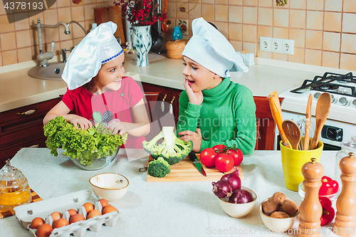 Image of happy family funny kids are preparing the a fresh vegetable salad in the kitchen