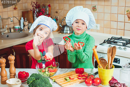 Image of happy family funny kids are preparing the a fresh vegetable salad in the kitchen