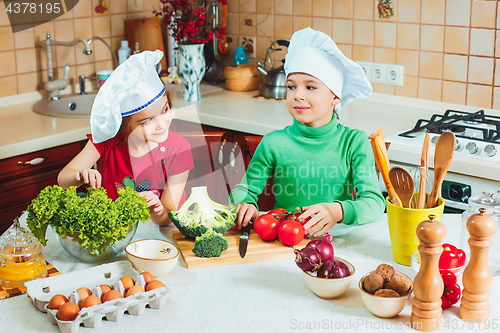 Image of happy family funny kids are preparing the a fresh vegetable salad in the kitchen