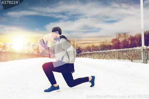 Image of man exercising and doing squats on winter bridge