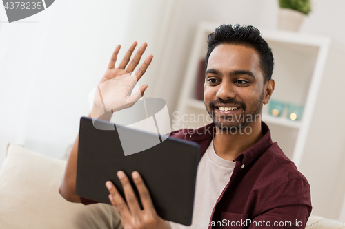 Image of happy man with tablet pc having video chat at home