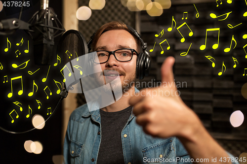 Image of man with headphones singing at recording studio