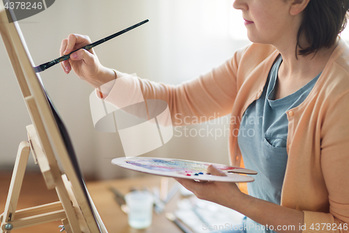 Image of artist with palette and brush painting at studio
