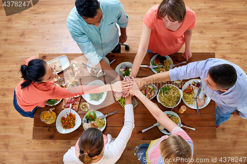 Image of people holding hands together over table with food