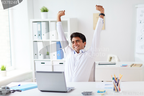 Image of tired businessman with laptop stretching at office