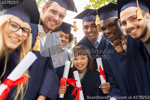 Image of happy students in mortar boards with diplomas