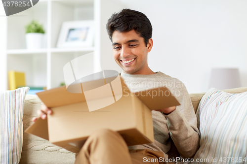 Image of happy man opening parcel box at home