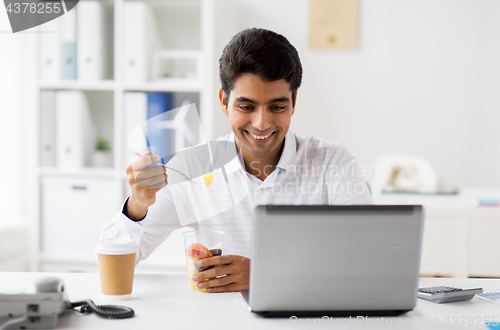 Image of businessman with laptop eating fruits at office