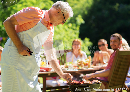 Image of senior man cooking meat on barbecue grill outdoors