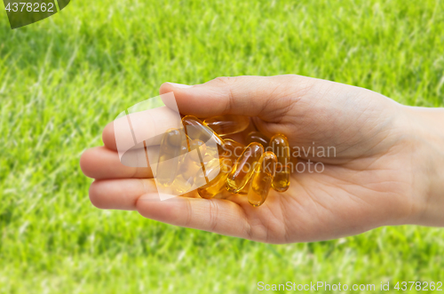 Image of hand holding cod liver oil capsules