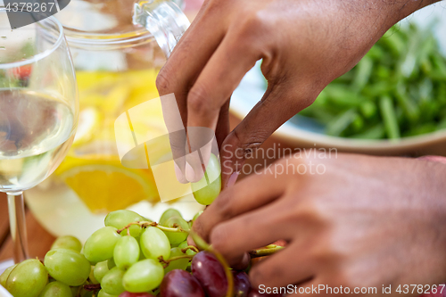 Image of hands taking grape from plate with fruits