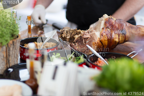 Image of Cheff serving traditional meat dish on street stall on street food festival, Ljubljana, Slovenia.