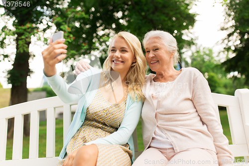 Image of daughter and senior mother taking selfie at park