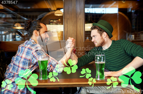 Image of men drinking green beer and arm wrestling at pub