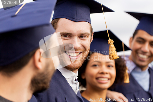 Image of happy students or bachelors in mortar boards