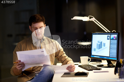 Image of designer with papers working at night office