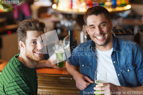 Image of male friends drinking green beer at bar or pub