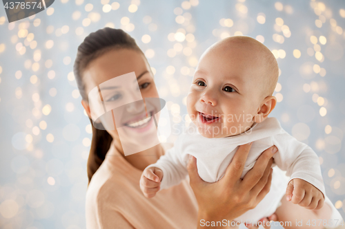 Image of happy mother playing with little baby over lights