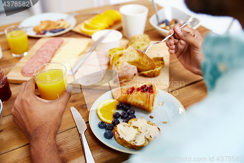 Image of close up of man eating croissant with orange juice