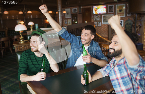 Image of happy male friends drinking beer at bar or pub