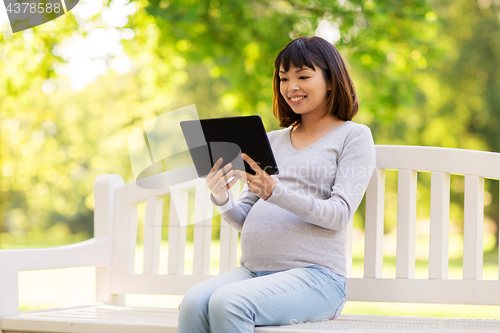 Image of happy pregnant asian woman with tablet pc at park