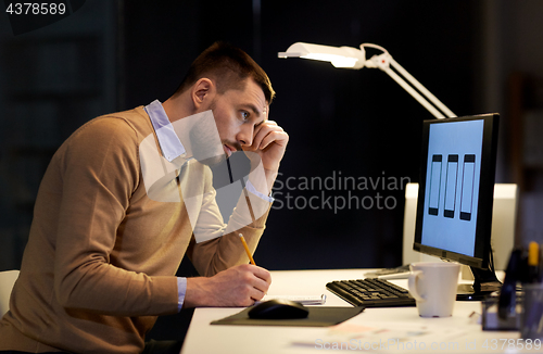 Image of man with notepad working at night office