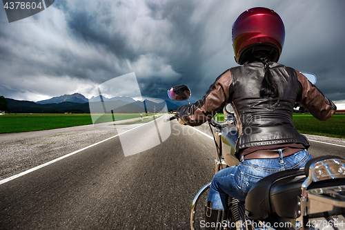 Image of Biker girl on a motorcycle hurtling down the road in a lightning