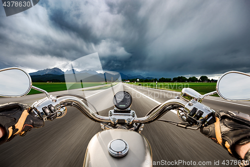 Image of Biker on a motorcycle hurtling down the road in a lightning stor