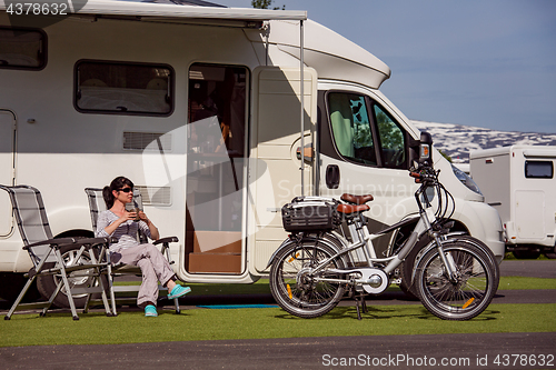 Image of Woman is standing with a mug of coffee near the camper RV.