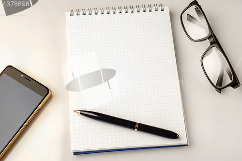 Image of Work space accessories: pen, notebook, glasses and a modern smartphone