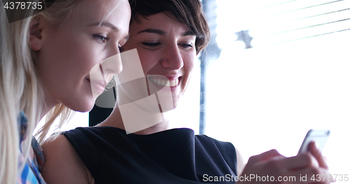 Image of two attractive business women with a cell phone discuss business