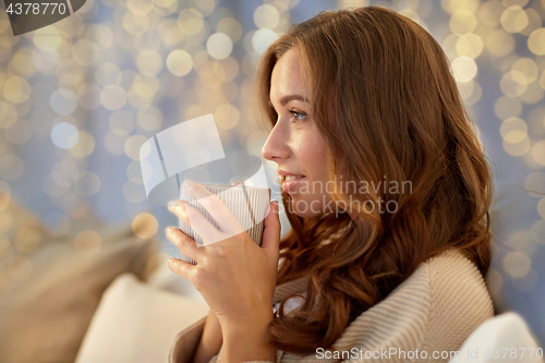 Image of happy woman with cup of coffee in bed at home