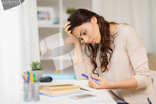 Image of tired female student with book learning at home