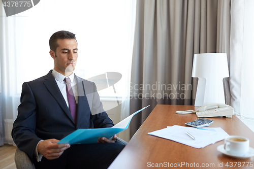 Image of businessman with papers working at hotel room