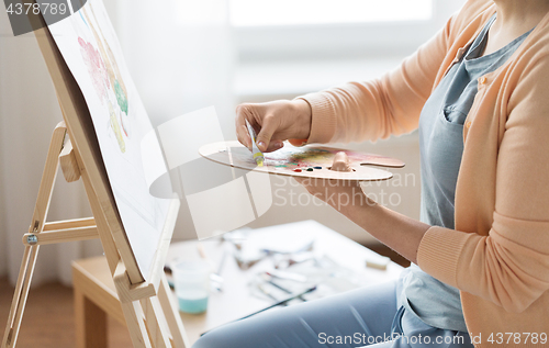 Image of artist applying paint to palette at art studio