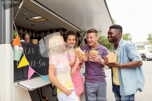 Image of happy friends with drinks eating at food truck