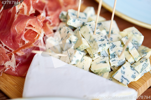 Image of blue cheese and jamon or parma ham on wooden board