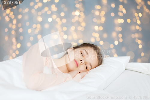 Image of girl sleeping in bed over holidays lights