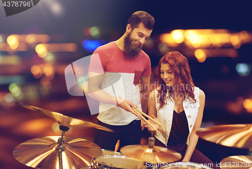 Image of man and woman with drum kit at music store