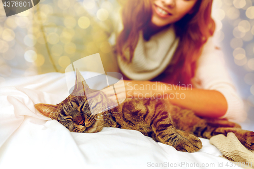 Image of happy young woman with cat lying in bed at home