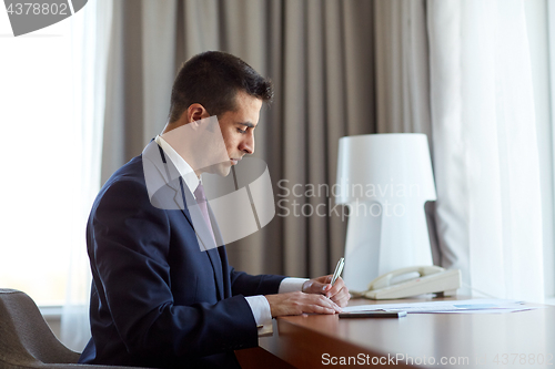 Image of businessman with papers working at hotel room