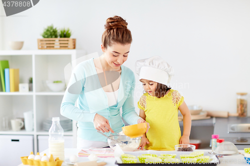Image of happy mother and daughter making dough at home